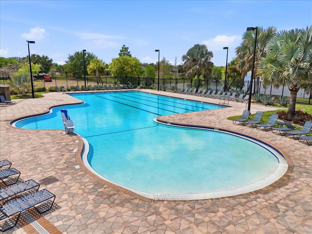 A large outdoor swimming pool with a paved deck and lounge chairs — 6431 COMO PLACE, LAKELAND, FL