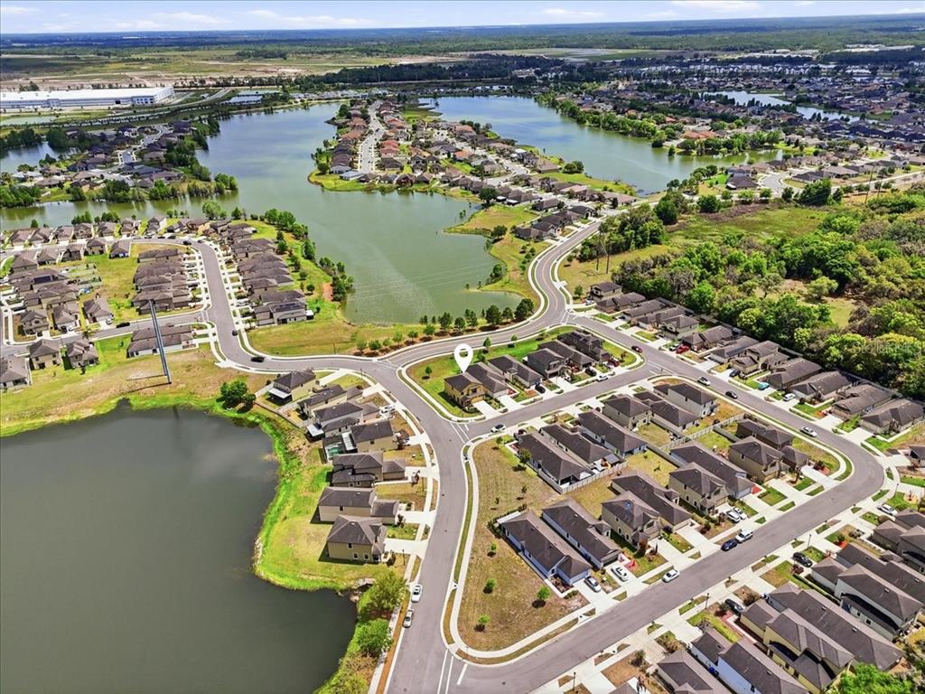 An aerial view shows a suburban neighborhood with houses surrounding a large lake — 6431 COMO PLACE, LAKELAND, FL