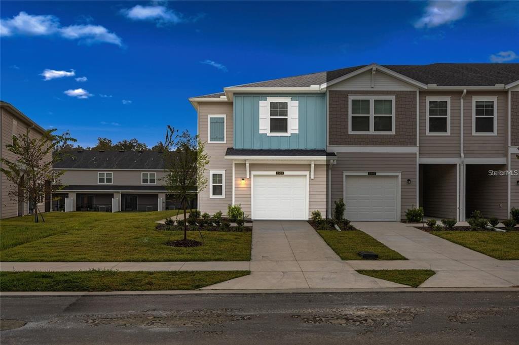 A two-story townhouse with a blue upper facade, a white garage, and a concrete driveway — 3644 SE 37TH COURT, OCALA, FL