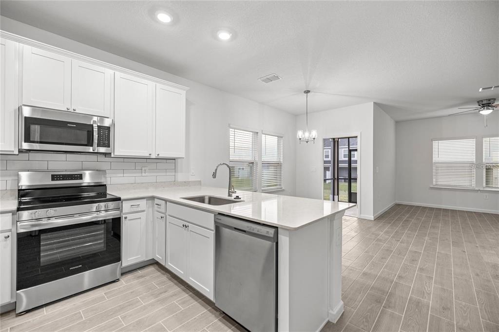 A modern kitchen features white cabinets, stainless steel appliances, and a quartz-topped island — 3644 SE 37TH COURT, OCALA, FL
