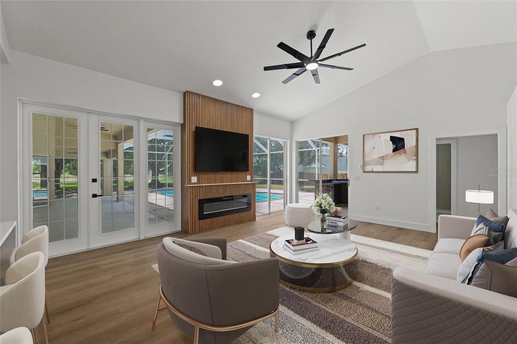 A living room with a slatted wood fireplace wall, vaulted ceiling, and sliding glass doors — 3519 SANDBURG LOOP, PLANT CITY, FL