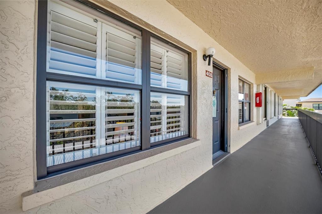 An exterior view of a building hallway featuring a window with shutters and a door — 625 30TH AVENUE W UNIT G408, BRADENTON, FL
