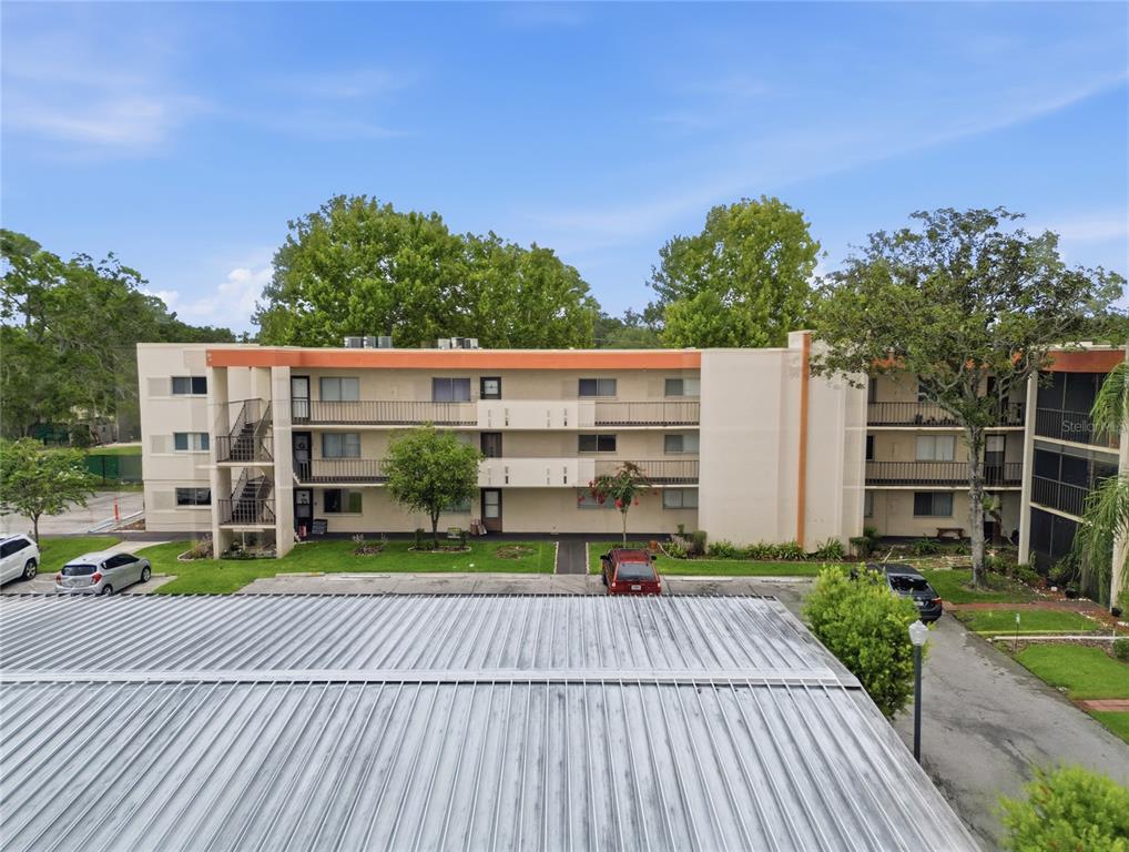 An exterior view of a three-story apartment building with a metal roof in the foreground — 1130 N LAKE PARKER AVENUE UNIT E233, LAKELAND, FL