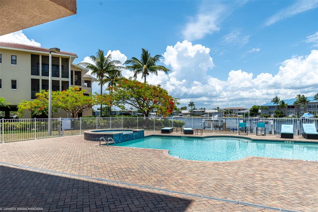 A swimming pool and hot tub are situated on a brick patio near a building — 3322 PURPLE MARTIN DR UNIT 132, PUNTA GORDA, FL