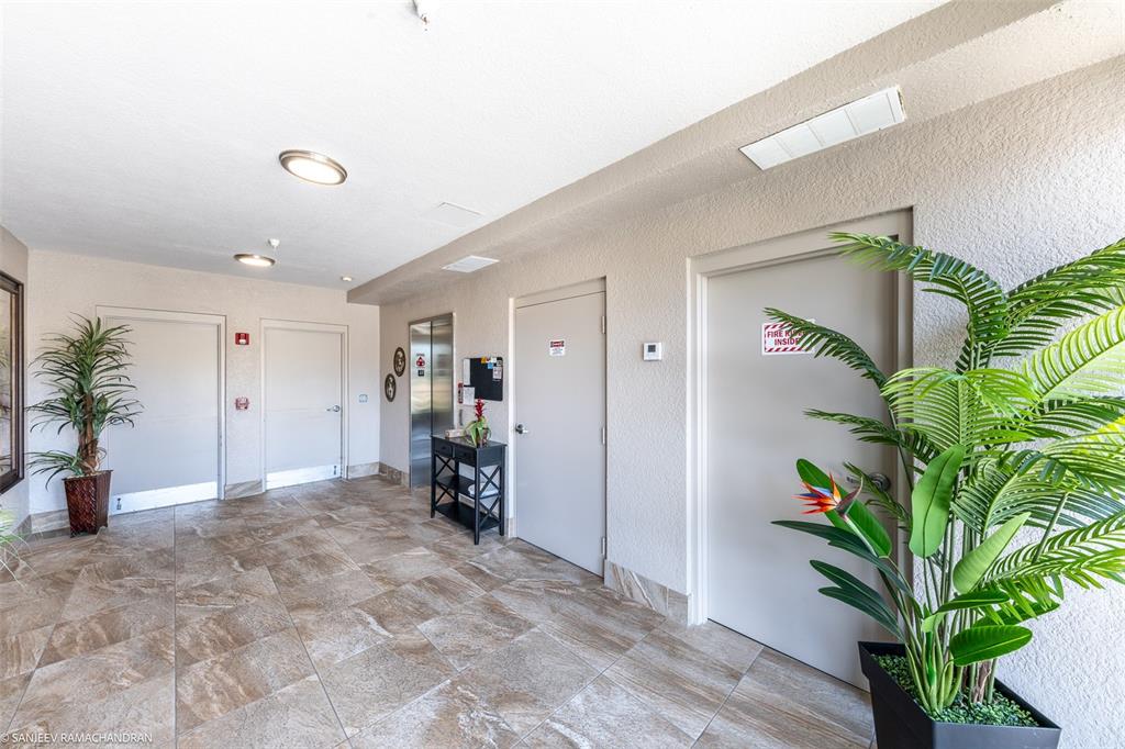 A tiled hallway features multiple doors, an elevator, and two potted plants — 3322 PURPLE MARTIN DR UNIT 132, PUNTA GORDA, FL