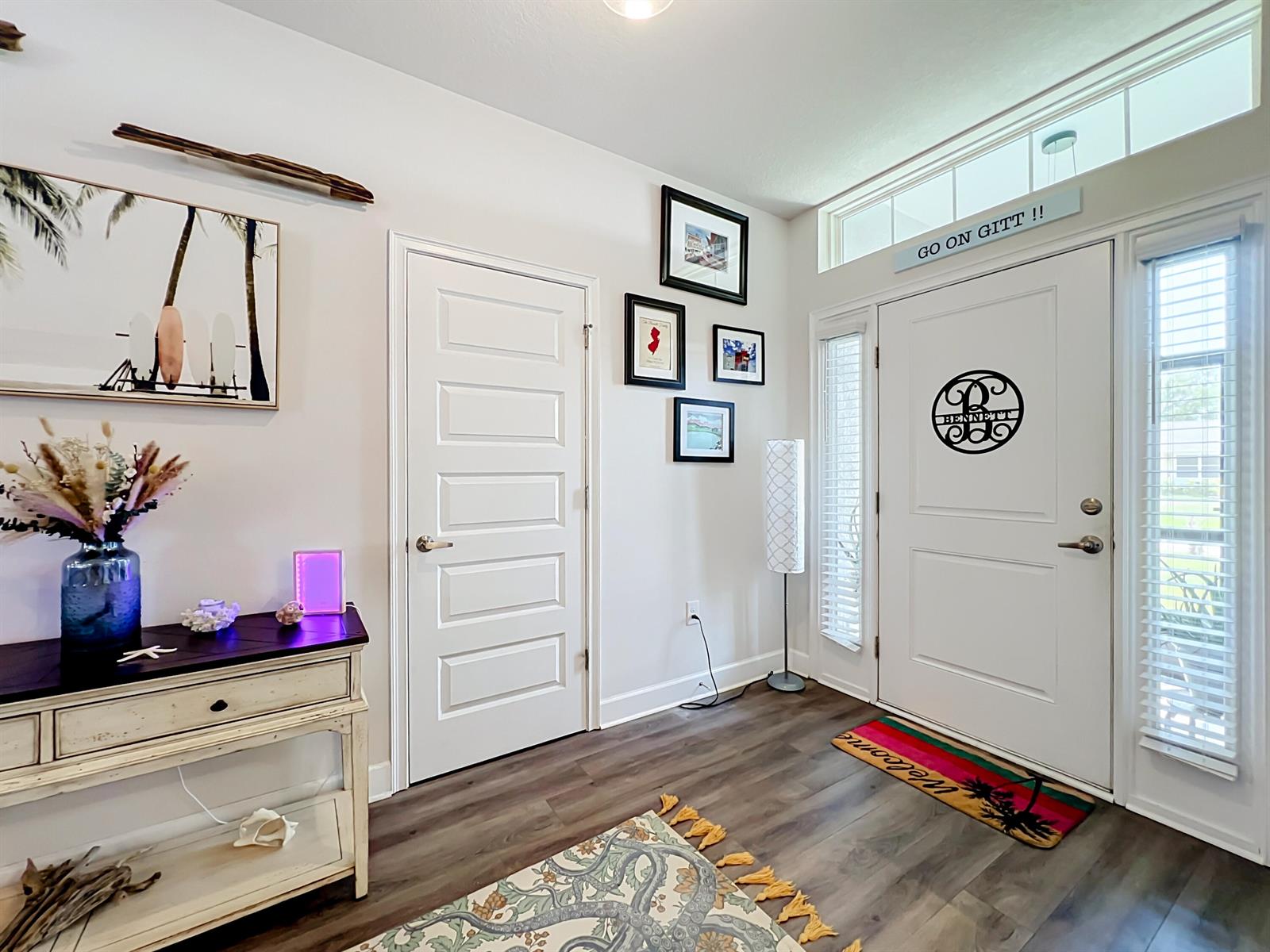 An entryway features a console table, a white door with a monogram, and framed wall art — 1574 Quiescent Lane, Sebastian FL 32958, SEBASTIAN, FL