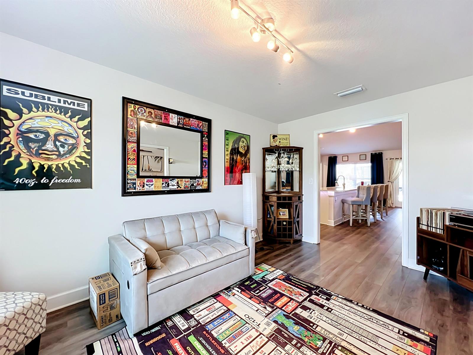 A living room features a light-colored sofa, a VHS-themed rug, and a corner display cabinet — 1574 Quiescent Lane, Sebastian FL 32958, SEBASTIAN, FL