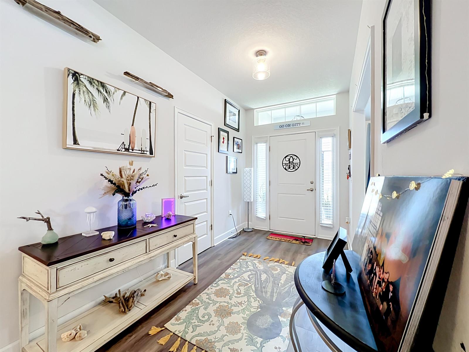 A bright entryway features a console table, a patterned rug, and a white front door — 1574 Quiescent Lane, Sebastian FL 32958, SEBASTIAN, FL