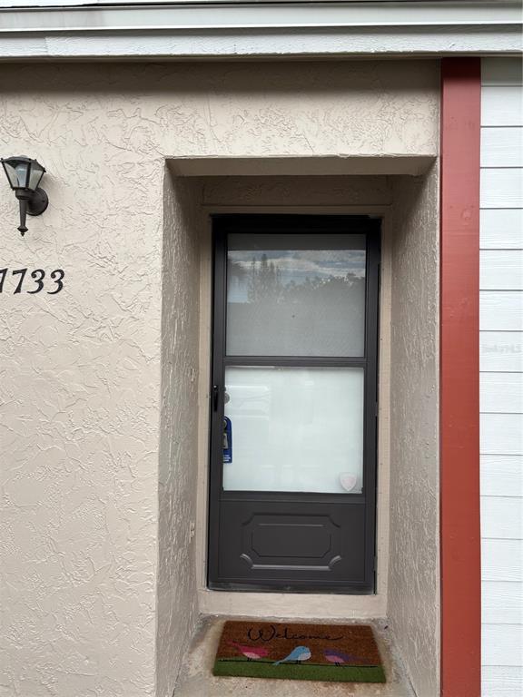 A front entrance with a dark storm door, a welcome mat, and a wall-mounted light — 7733 COUNTRY PLACE UNIT G2, WINTER PARK, FL