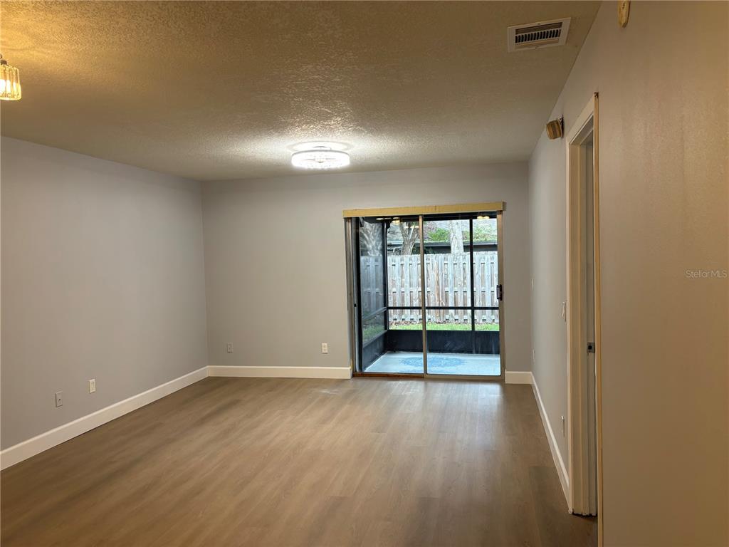 A living room with light gray walls, wood-look flooring, and a sliding glass door — 7733 COUNTRY PLACE UNIT G2, WINTER PARK, FL