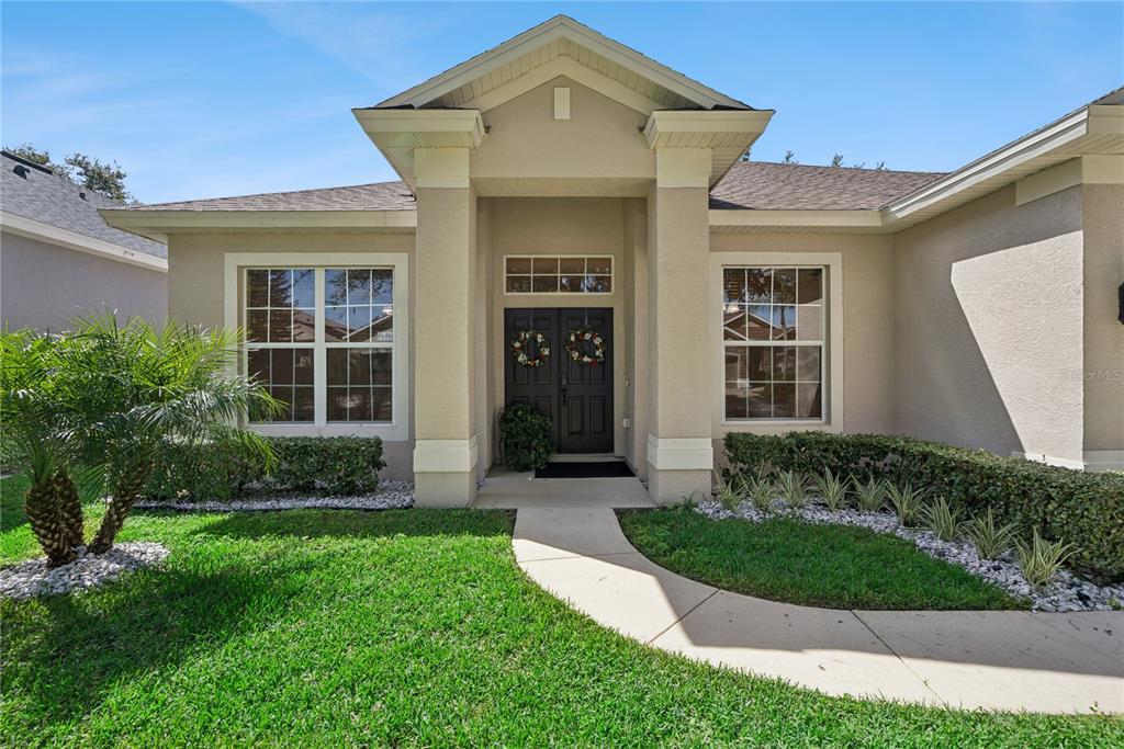 The exterior of a beige house features a covered entryway with a double front door — 1040 KERSFIELD CIRCLE, LAKE MARY, FL
