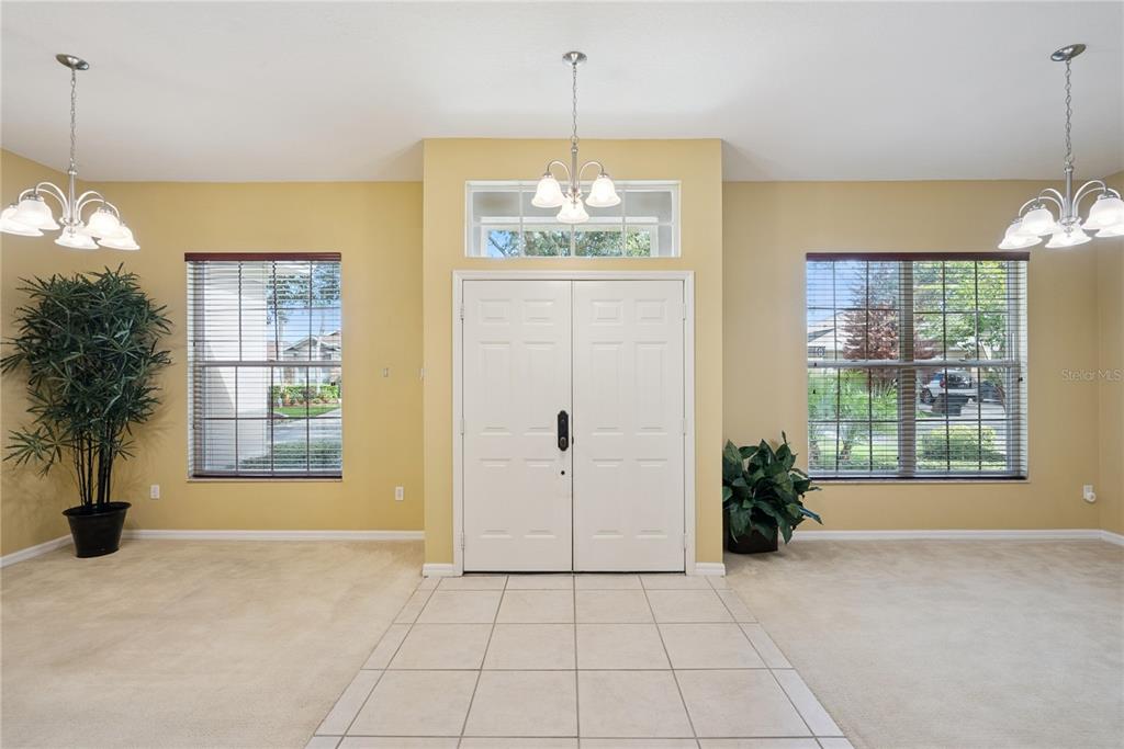 An entryway features a tiled floor, beige carpet, double doors, and two matching chandeliers — 1040 KERSFIELD CIRCLE, LAKE MARY, FL