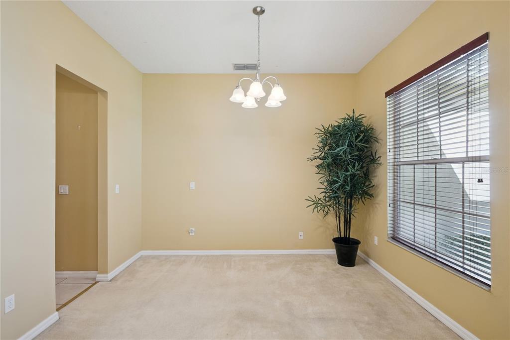 An empty dining room with beige walls, carpeted flooring, a chandelier, and a potted plant — 1040 KERSFIELD CIRCLE, LAKE MARY, FL