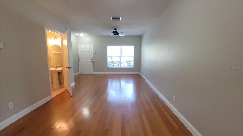 An empty room features light wood flooring, a ceiling fan, and an adjacent bathroom door — 6235 BAYSIDE KEY DRIVE, TAMPA, FL
