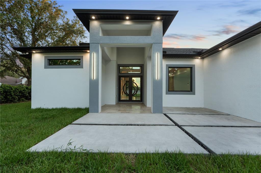 The exterior of a modern home features a covered entryway with double glass doors — 9201 NIGHTINGALE ROAD, WEEKI WACHEE, FL