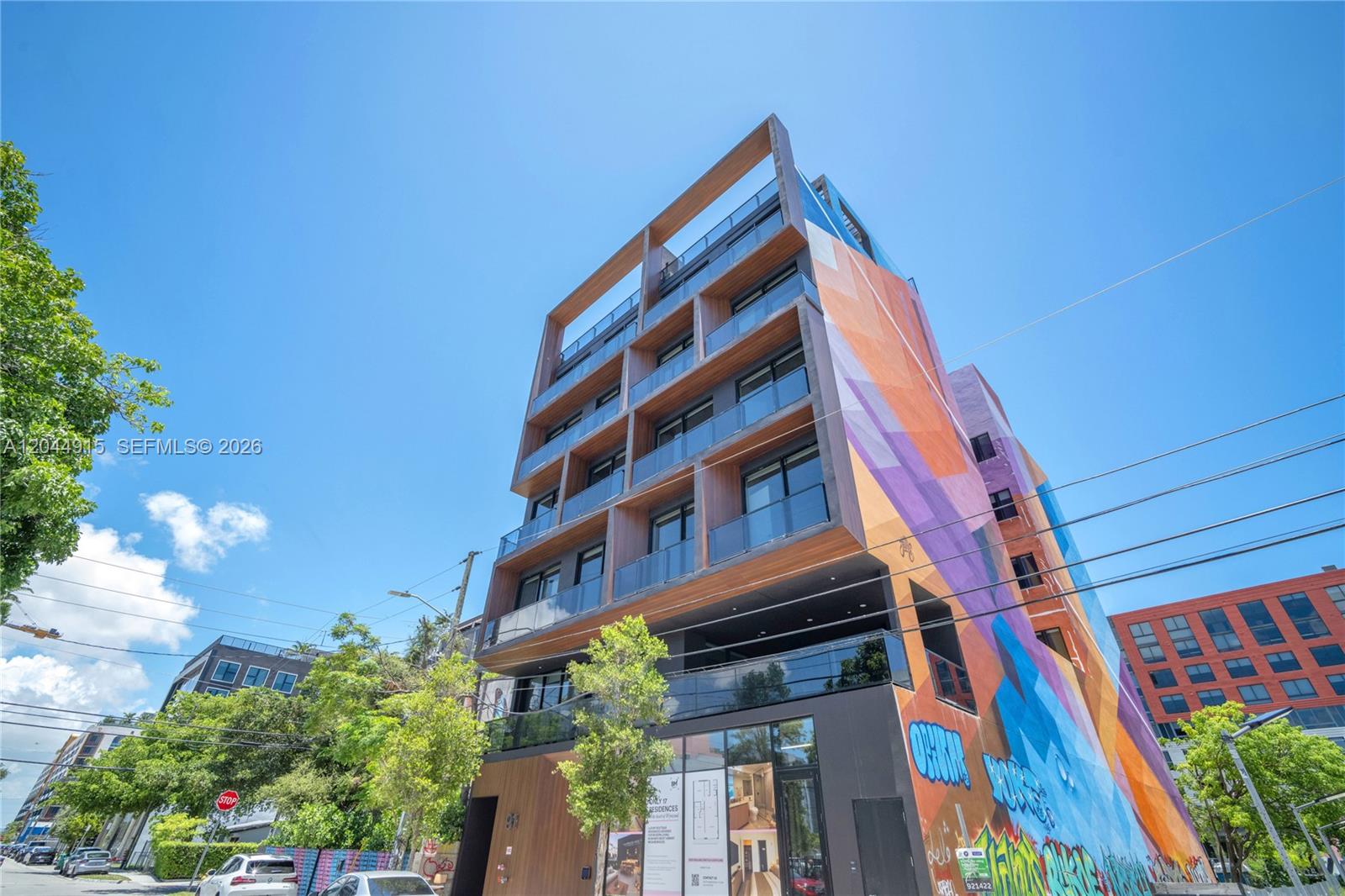 A modern multi-story residential building features wood-paneled balconies and a large, colorful mural — 91 NW 27th St # 503, Miami FL 33127, MIAMI, FL