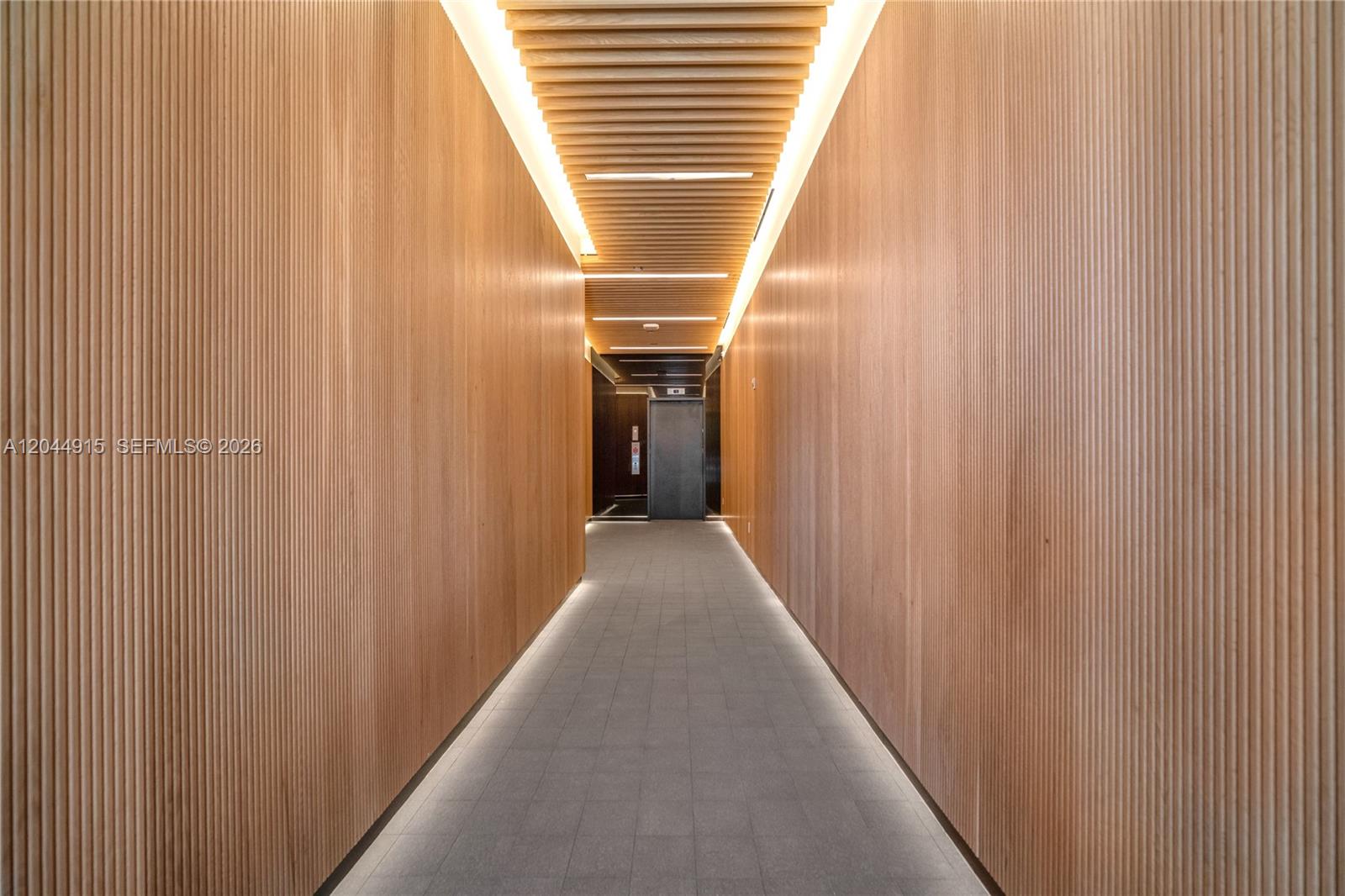A narrow hallway features vertical wood-slatted walls, a slatted ceiling, and recessed floor lighting — 91 NW 27th St # 503, Miami FL 33127, MIAMI, FL