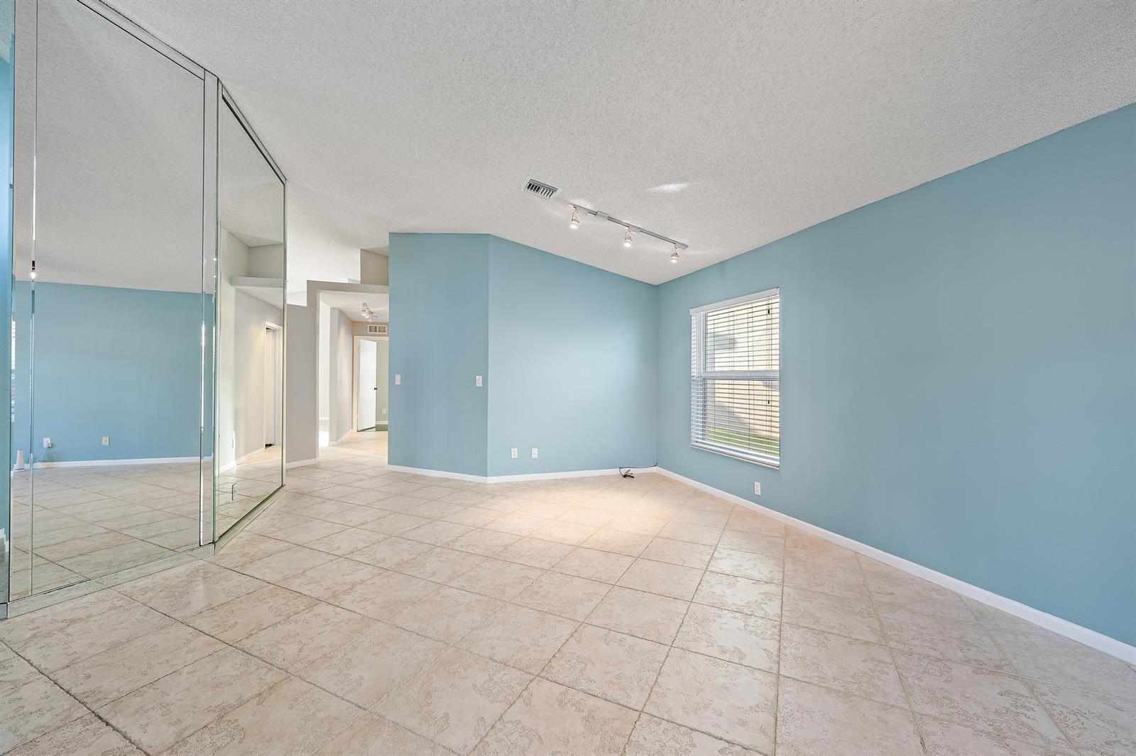 An empty living room features light blue walls, tile flooring, a ceiling fan, and entryway — 8657 Tourmaline Boulevard, Boynton Beach FL 33472, BOYNTON BEACH, FL