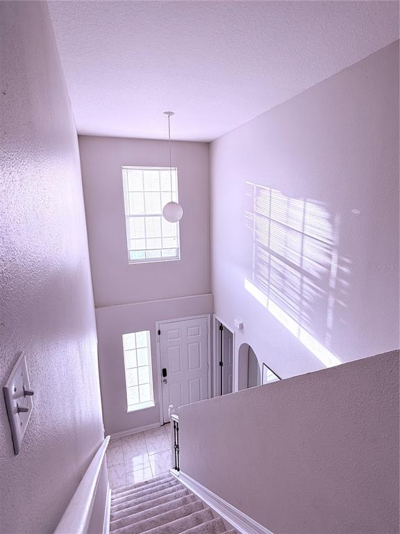The rear exterior of a two-story white house features a sliding glass door and windows — 5764 ROYAL HILLS CIRCLE, WINTER HAVEN, FL