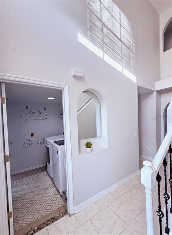 A view from a carpeted staircase looking down into a two-story foyer with tile flooring — 5764 ROYAL HILLS CIRCLE, WINTER HAVEN, FL