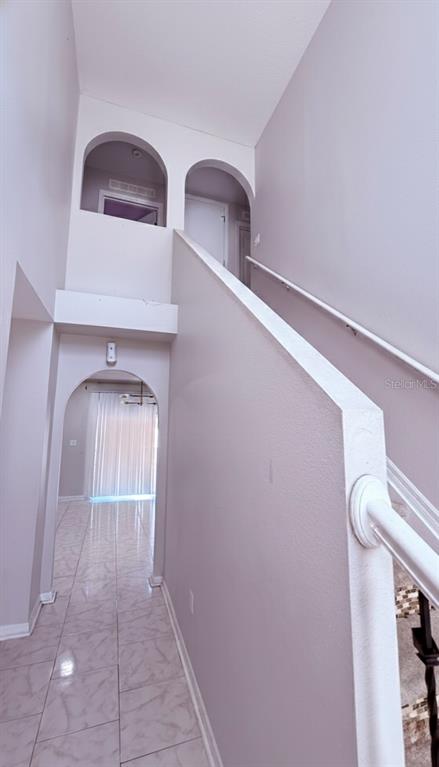 A laundry room with a patterned rug sits beside an arched wall niche and staircase — 5764 ROYAL HILLS CIRCLE, WINTER HAVEN, FL