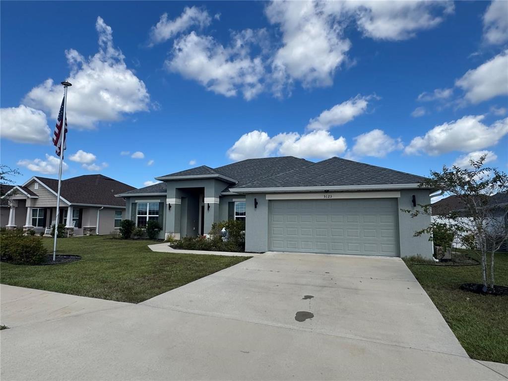 A single-story suburban house with a gray exterior, a two-car garage, and a flag pole — 5123 SW 91ST STREET, OCALA, FL