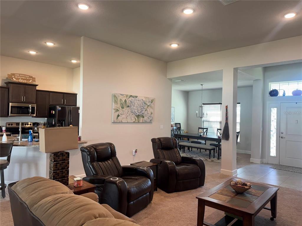 A living room with leather recliners and a coffee table opens to a kitchen and dining area — 5123 SW 91ST STREET, OCALA, FL