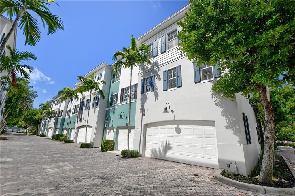 A row of multi-story townhomes with white garages and blue shutters along a paved driveway — 306 E Mallory Circle, Delray Beach FL 33483, DELRAY BEACH, FL