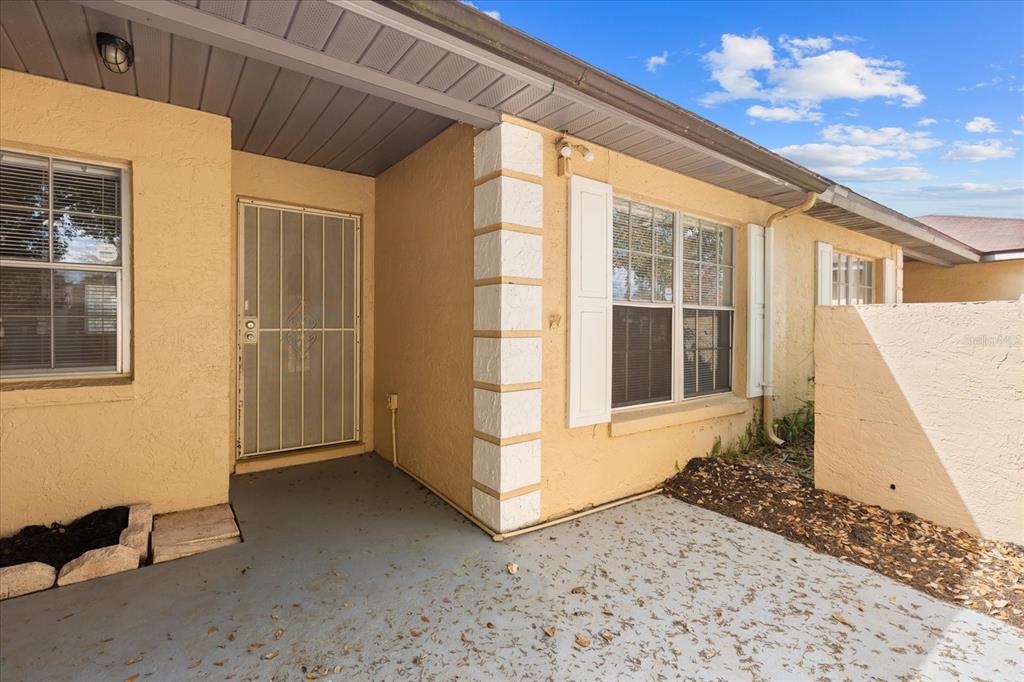 A tan stucco house exterior features a covered entryway, a security door, and a patio — 1444 SOPHIE BOULEVARD, ORLANDO, FL