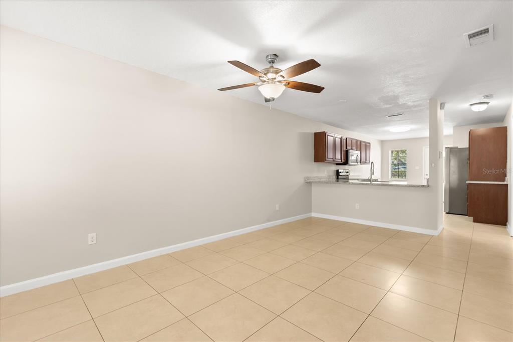 An open-concept living area with tile flooring, a ceiling fan, and an adjacent kitchen — 1444 SOPHIE BOULEVARD, ORLANDO, FL