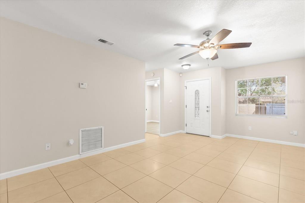 A bright living room features light-colored tile flooring, a ceiling fan, and a front door — 1444 SOPHIE BOULEVARD, ORLANDO, FL