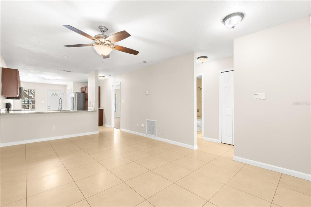 An open-concept living area features light tile flooring, a ceiling fan, and a kitchen pass-through — 1444 SOPHIE BOULEVARD, ORLANDO, FL