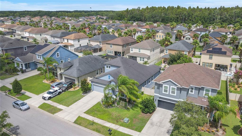 An aerial view shows a suburban neighborhood with multiple single-family homes and parked cars — 1571 MONTGOMERY BELL RD, WESLEY CHAPEL, FL