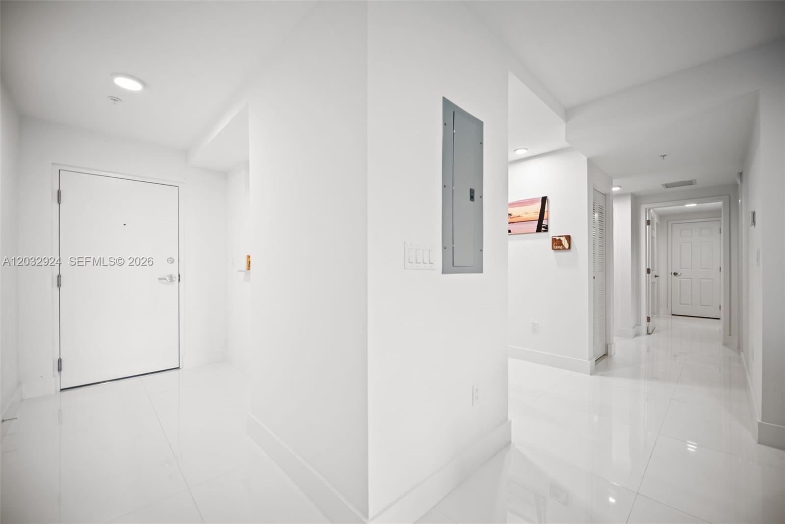 A bright white entryway features glossy tile floors, a gray electrical panel, and a hallway — 10950 NW 82nd St # 213, Doral FL 33178, DORAL, FL
