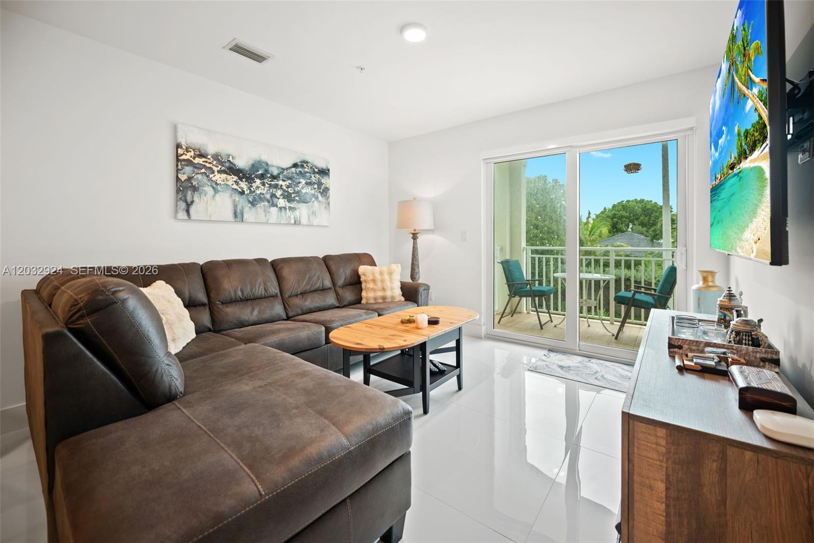 A living room features a dark brown sectional sofa, a wooden coffee table, and a balcony — 10950 NW 82nd St # 213, Doral FL 33178, DORAL, FL