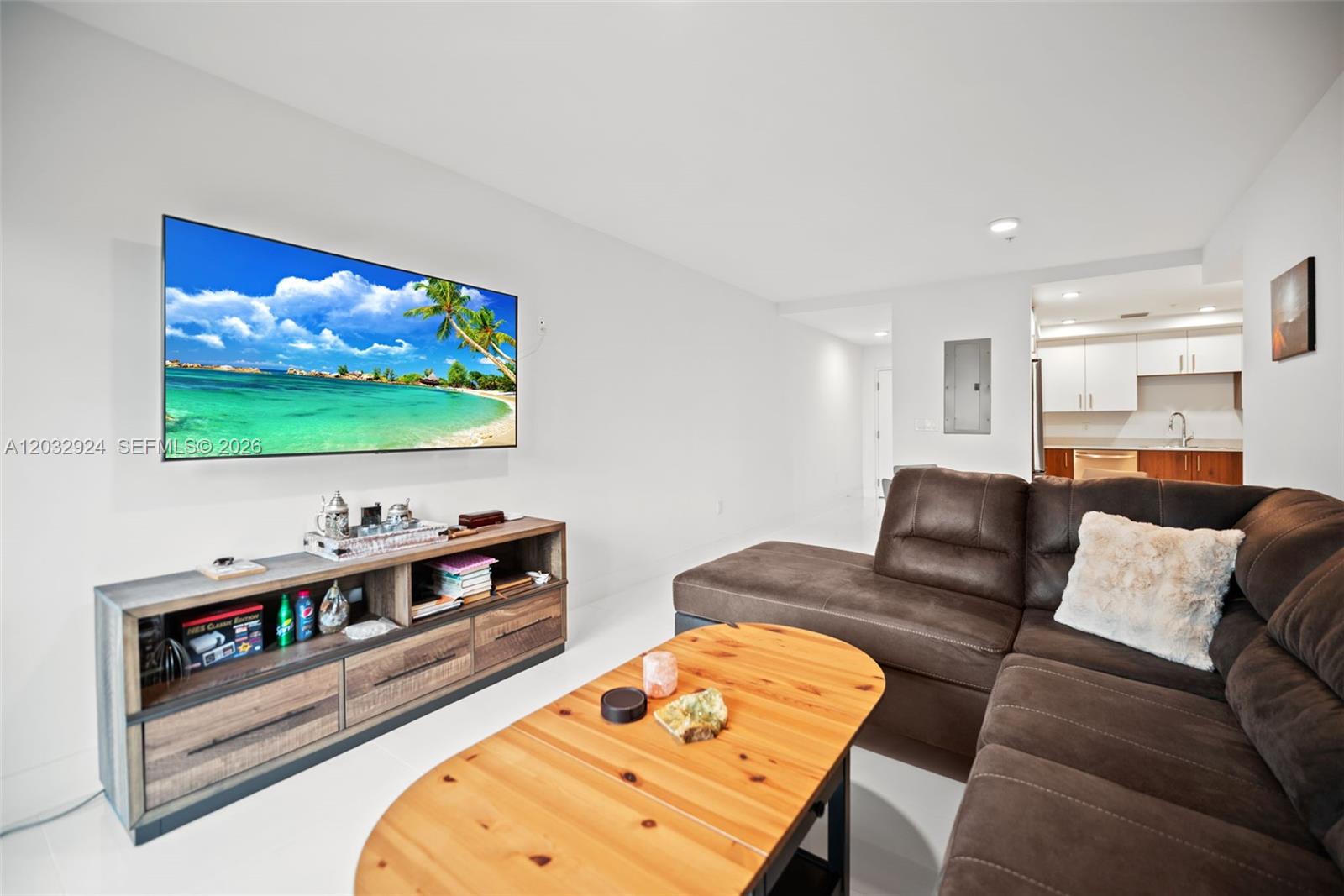 A living room features a wall-mounted television, a wooden media console, and a brown sectional — 10950 NW 82nd St # 213, Doral FL 33178, DORAL, FL