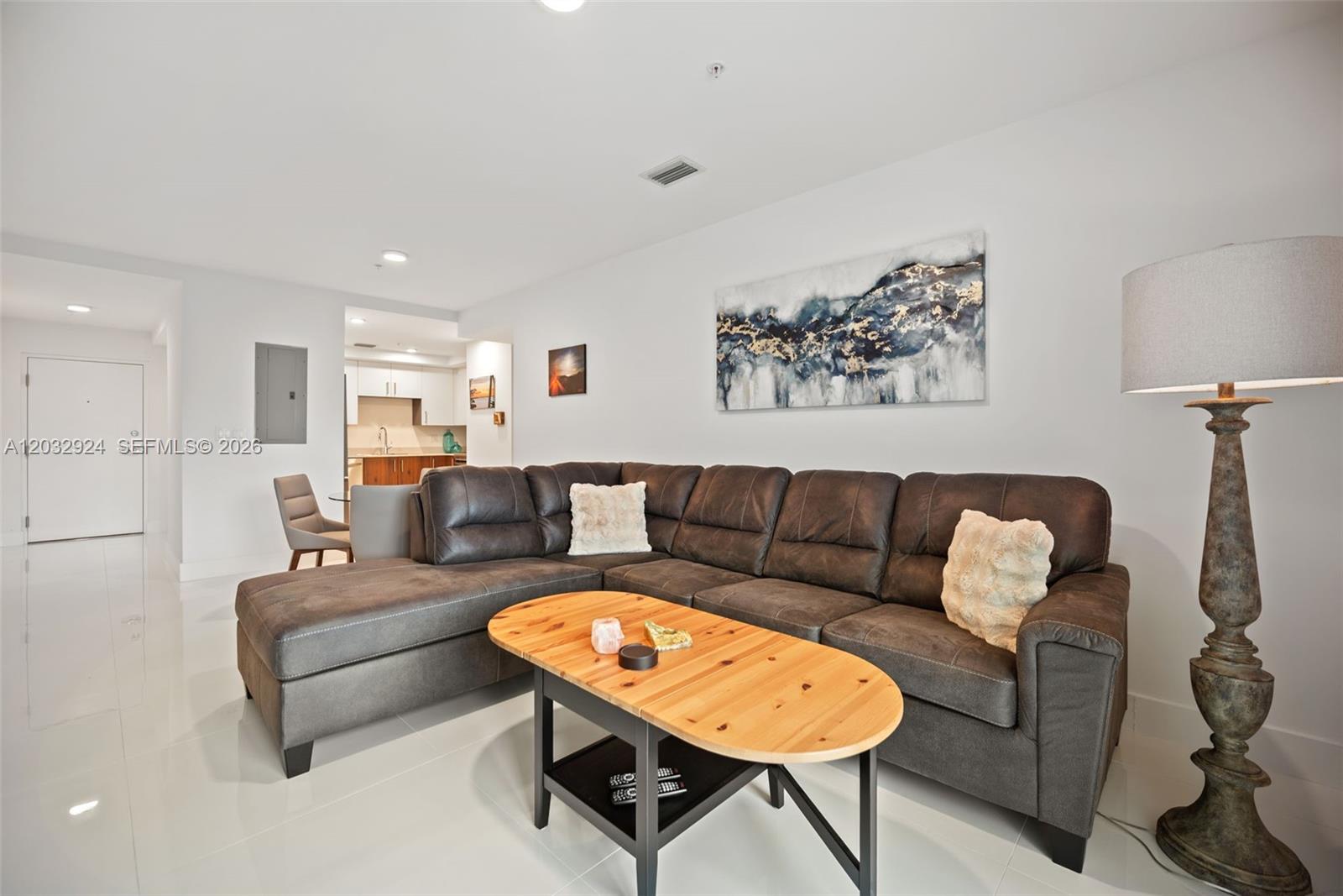 A living room features a dark sectional sofa, a wooden coffee table, and a floor lamp — 10950 NW 82nd St # 213, Doral FL 33178, DORAL, FL