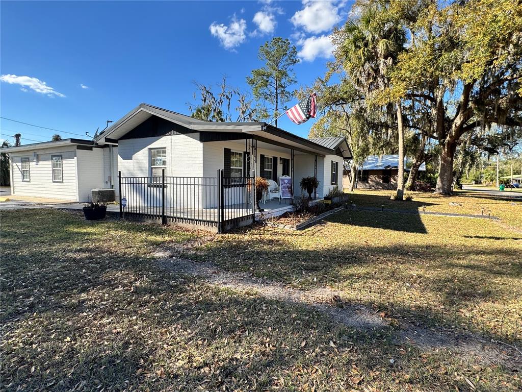 A white, single-story house with a black metal fence and an American flag on display — 304 NE 1ST STREET, CHIEFLAND, FL