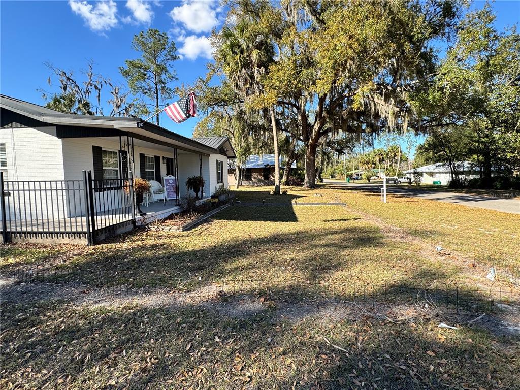 A white house with a covered porch and an American flag stands on a lawn — 304 NE 1ST STREET, CHIEFLAND, FL