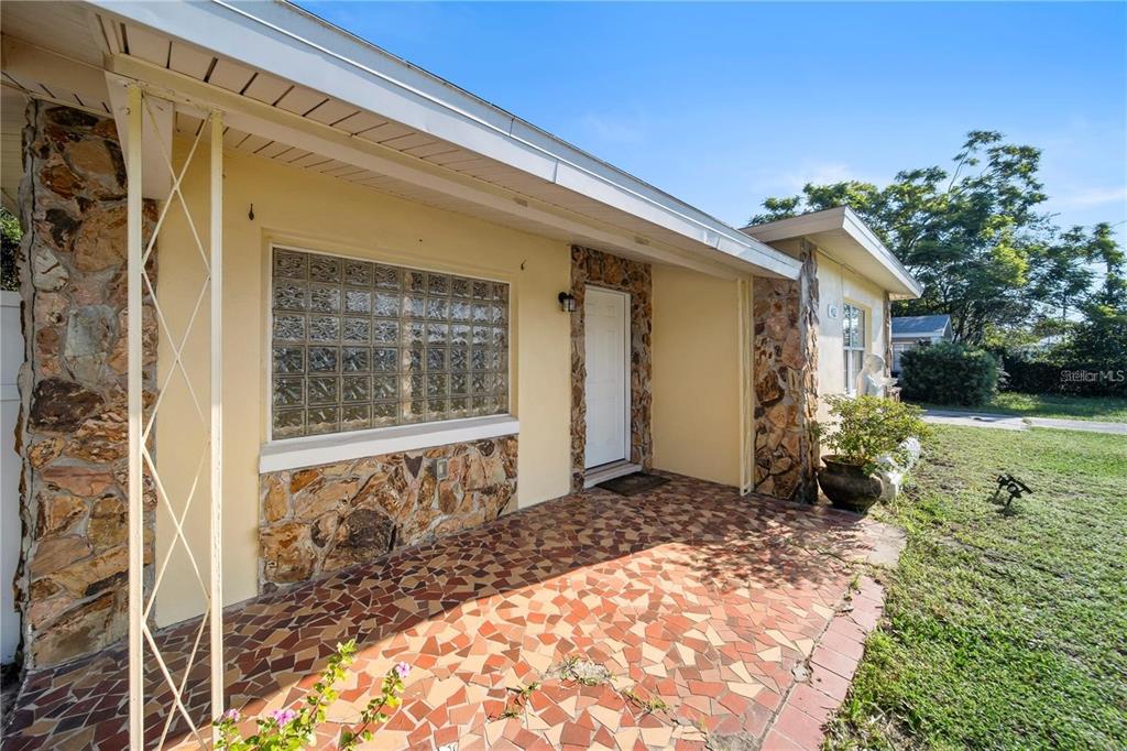 A covered front porch features a tiled floor, stone accents, and a glass block window — 402 TUSCARORA STREET, LAKELAND, FL