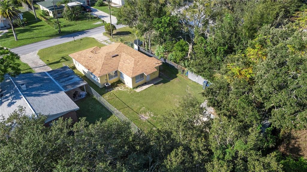 An aerial view shows a yellow house with a brown roof and a fenced backyard — 402 TUSCARORA STREET, LAKELAND, FL
