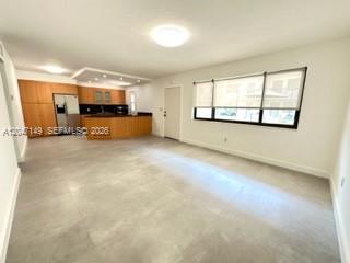 An open-concept kitchen and living area with light-colored tile flooring and wooden cabinetry — 2924 Day Ave # N114, Miami FL 33133, MIAMI, FL