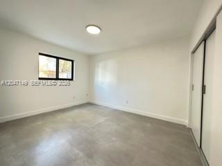 A bright, empty bedroom features white walls, gray tile flooring, and a sliding closet door — 2924 Day Ave # N114, Miami FL 33133, MIAMI, FL