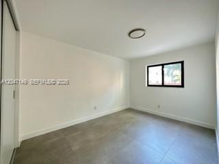 A bedroom with white walls, gray tile flooring, a closet, and a window — 2924 Day Ave # N114, Miami FL 33133, MIAMI, FL