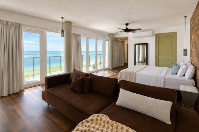 A bedroom with a brown sofa, a bed, and floor-to-ceiling windows overlooking the ocean — 14 CAMINO LAS PICUAS, RIO GRANDE, PR