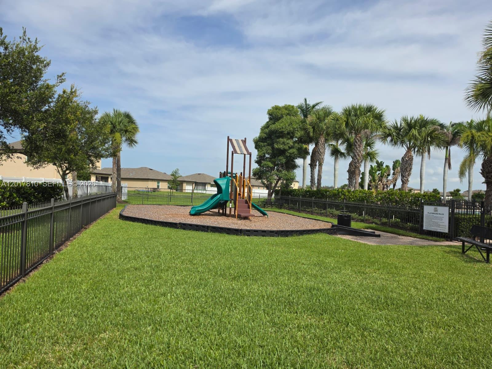 A playground with a slide and climbing structure sits on a wood-chipped area outdoors — 831 Bent Creek Dr, Fort Pierce FL 34947, FORT PIERCE, FL