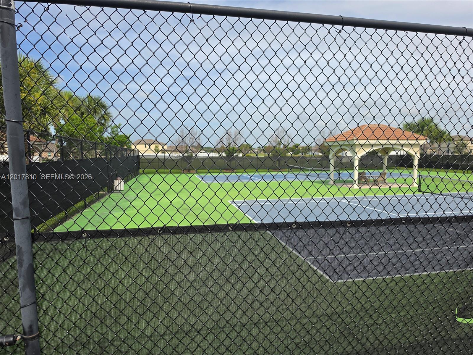 A chain-link fence overlooks a tennis court with a gazebo in the background — 831 Bent Creek Dr, Fort Pierce FL 34947, FORT PIERCE, FL
