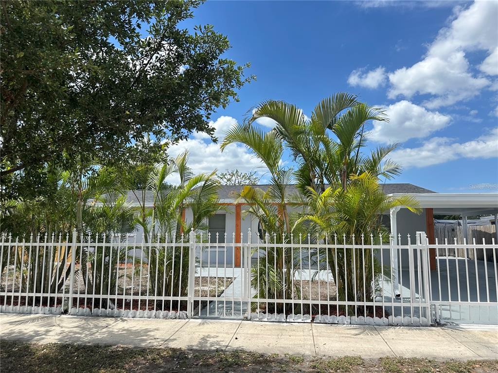 A single-story house with a white fence and palm trees in the front yard — 6405 S MANHATTAN AVENUE, TAMPA, FL