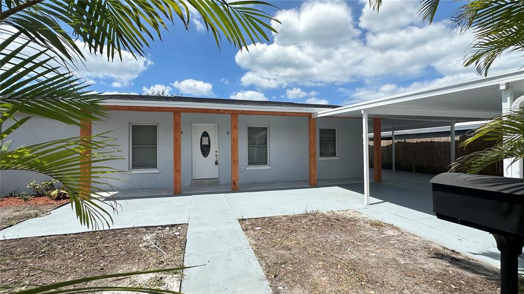 A single-story house with a gray exterior, wooden porch posts, and an attached carport — 6405 S MANHATTAN AVENUE, TAMPA, FL