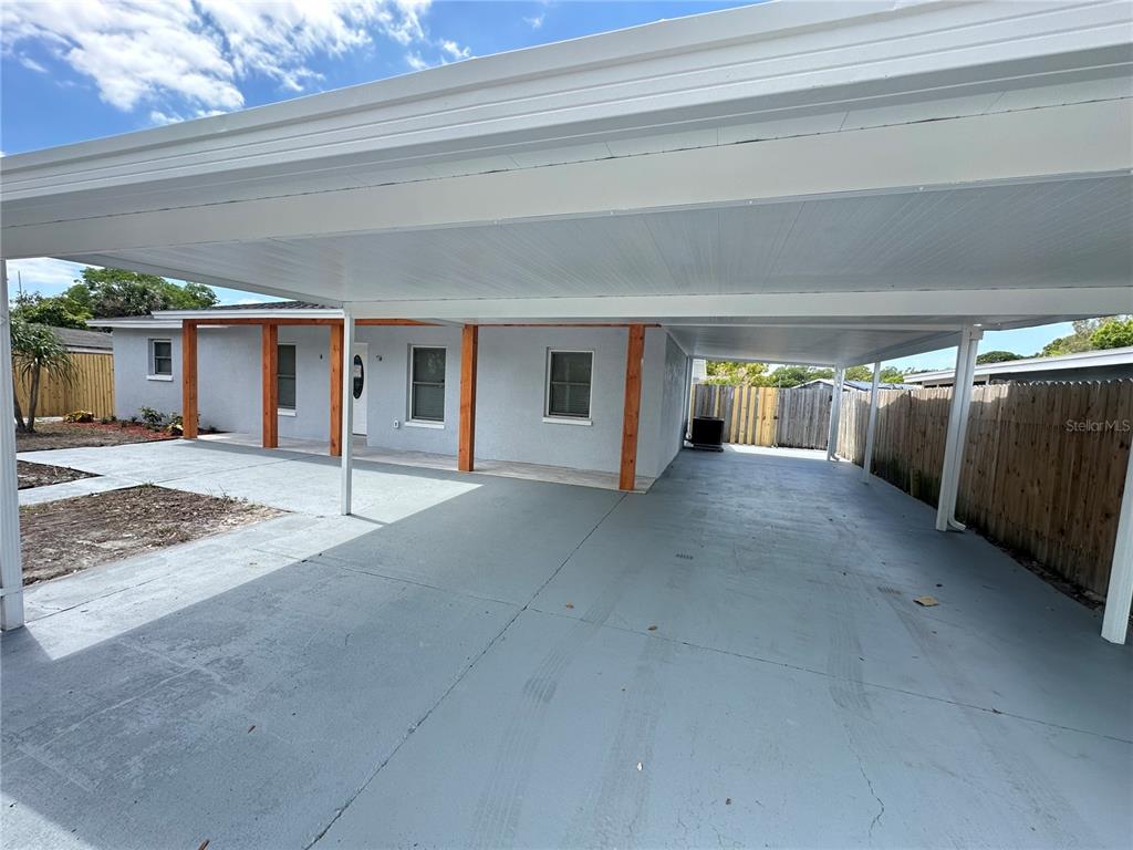 A gray concrete driveway is covered by a large white carport attached to a house — 6405 S MANHATTAN AVENUE, TAMPA, FL
